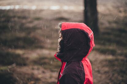 Un niño camina bajo la lluvia.