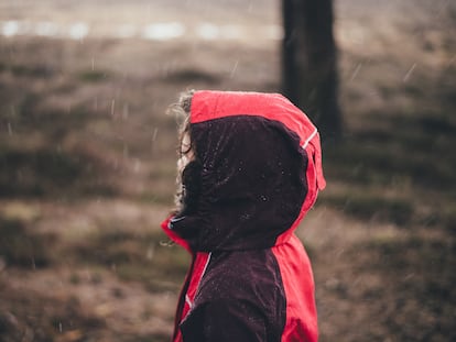 Un niño camina bajo la lluvia.