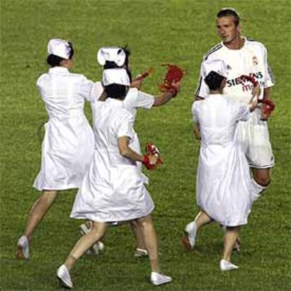 Varias enfermeras chinas se acercan a David Beckham para obsequiarle con recuerdos poco antes del partido.