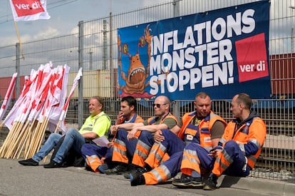 Cinco trabajadores sentados ante una pancarta que reza "Alto al monstruo de la inflación", durante una huelga a comienzos de junio en el puerto de Hamburgo.