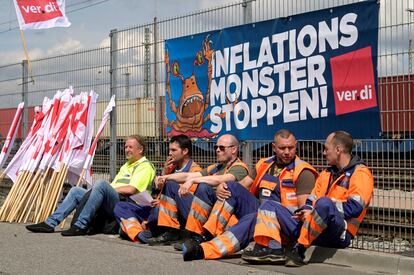 Cinco trabajadores sentados ante una pancarta que reza "Alto al monstruo de la inflación", durante una huelga a comienzos de junio en el puerto de Hamburgo.