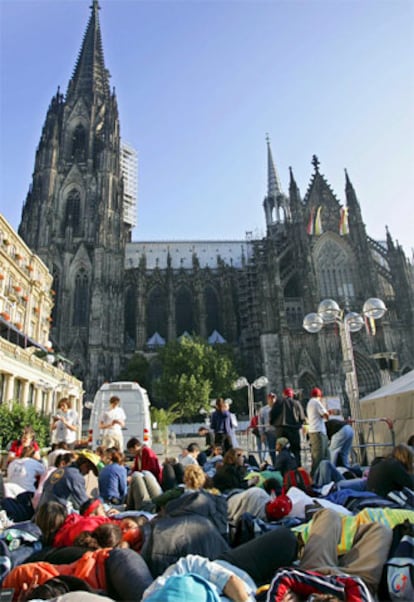 Jóvenes asistentes a las jornadas de la Juventud en Colonia descansan frente a la catedral.