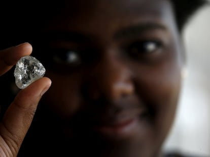 A visitor holds a precious stone during a visit to the headquarters of the De Beers diamond company in Gaborone, Botswana.