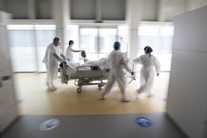 Personal sanitario traslada a un paciente por el pasillo de un hospital.