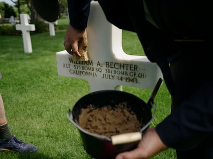 The Burridge family places sand on the grave of William A. Bechter, a family friend, in the American Cemetery in the town of Colleville-sur-mer.