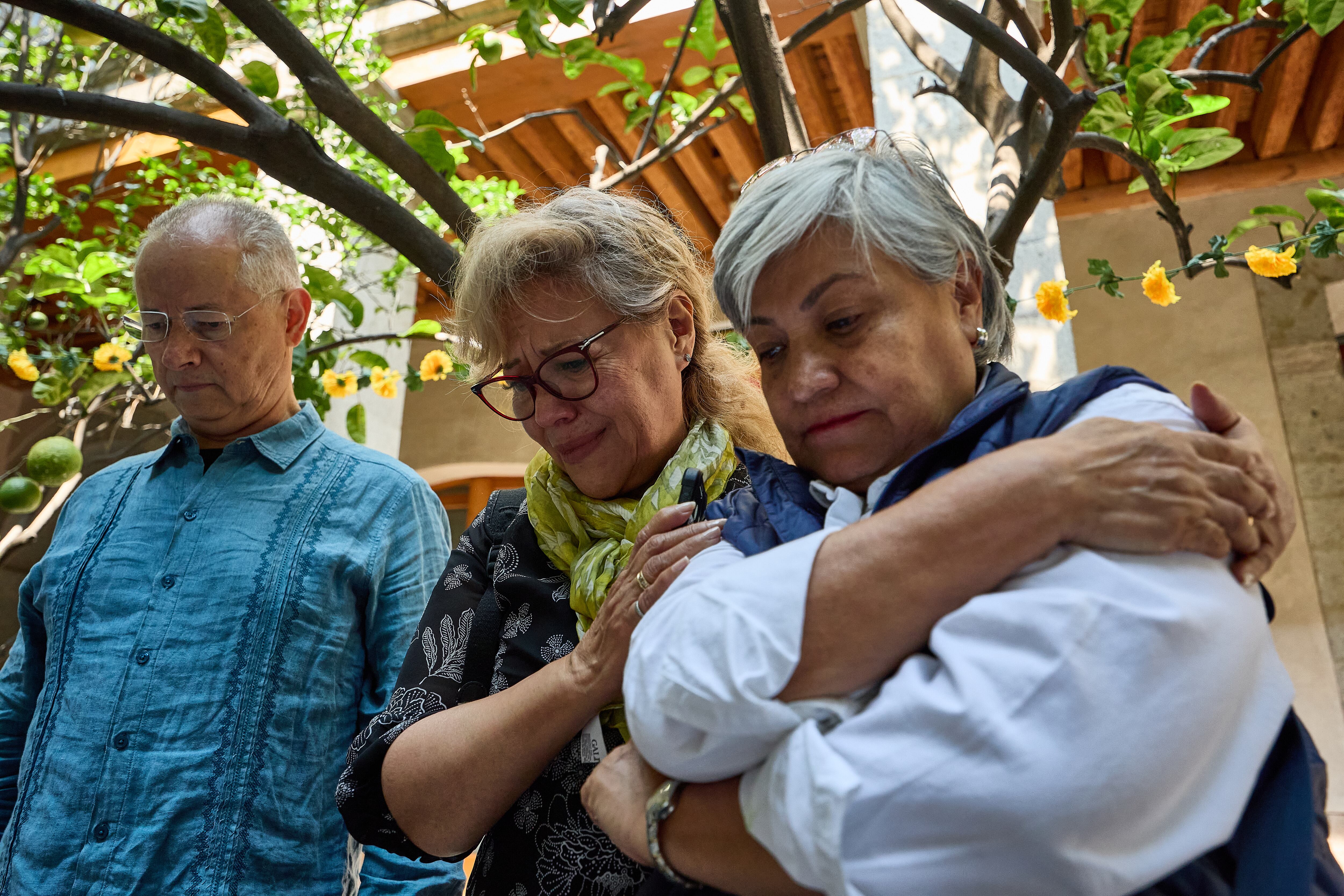 Daniel Reyes junto a las hermanas Patricia y Camelia Leyva, asistentes del evento, se conmueven al ver escrito el nombre de un familiar fallecido, este domingo en El Colegio Nacional.