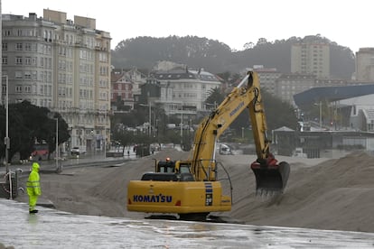Una excavadora reforzaba las dunas artificiales de la playa de Riazor para que sirvan de protección contra el oleaje y el viento, este jueves en A Coruña. 