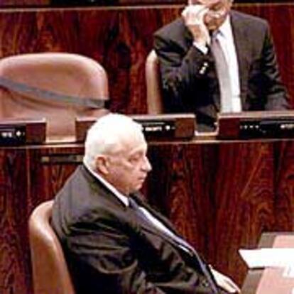 El primer ministro israelí, Ariel Sharon, sentado frente al escaño, con una cinta negra, del ministro asesinado.