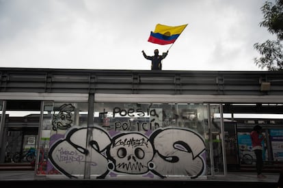 Un manifestante con la bandera de Colombia protesta sobre una estación de bus en la ciudad de Bogotá.
