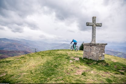 Un ciclista culmina el alto del Acebo, que ofrece una vasta vista del paisaje montañoso asturiano.