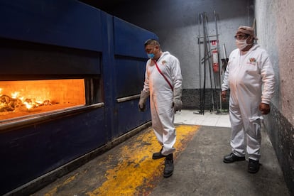 Dos empleados observan la incineración del cadáver de una víctima de coronavirus, en el crematorio de Iztapalapa (Ciudad de México).