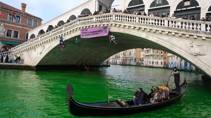 People ride in boats as waters of Grand Canal turned green after a protest by 'Extinction Rebellion' climate activists in Venice, Italy, December 9, 2023. REUTERS/Manuel Silvestri