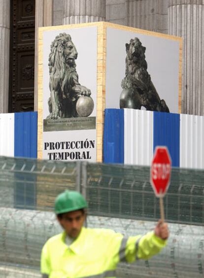 Un obrero, delante de las cajas que protegen los leones del Congreso de los Diputados.