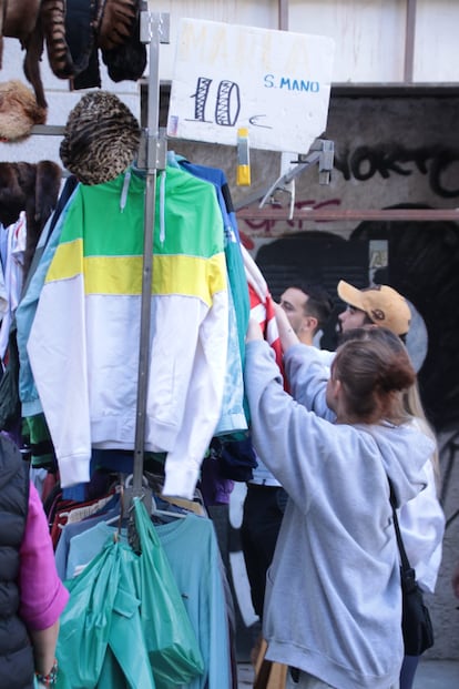 Un grupo de jóvenes ojea la ropa que hay en uno de los puestos de el Rastro de Madrid. 