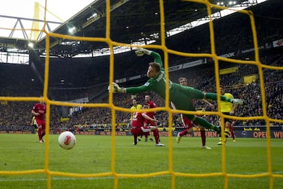 El portero del Friburgo Oliver Baumann salta para tratar de detener el lanzamiento del delantero del Borussia Dortmund Robert Lewandowski (derecha), que marcó el primer gol de su equipo (e hizo doblete con otro tanto en el minuto 45), durante el partido de la Bundesliga disputado en el estadio Signal Iduna Park, en Dortmund, Alemania.