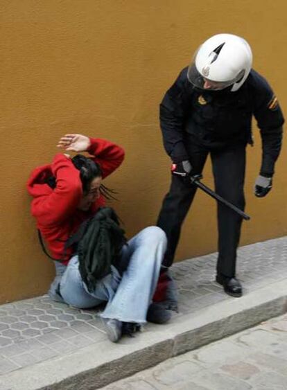 Una joven que se resistió a abandonar el edificio sale del escoltada por la policía.