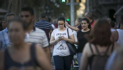 Una joven pasea con la mirada fija en la pantalla.