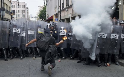 Un encapuchado lanza un cóctel molotov a la policía.