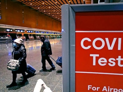 Dos viajeros pasan ante una señal de tests de covid, el pasado 21 de diciembre en el aeropuerto Logan, en Boston.