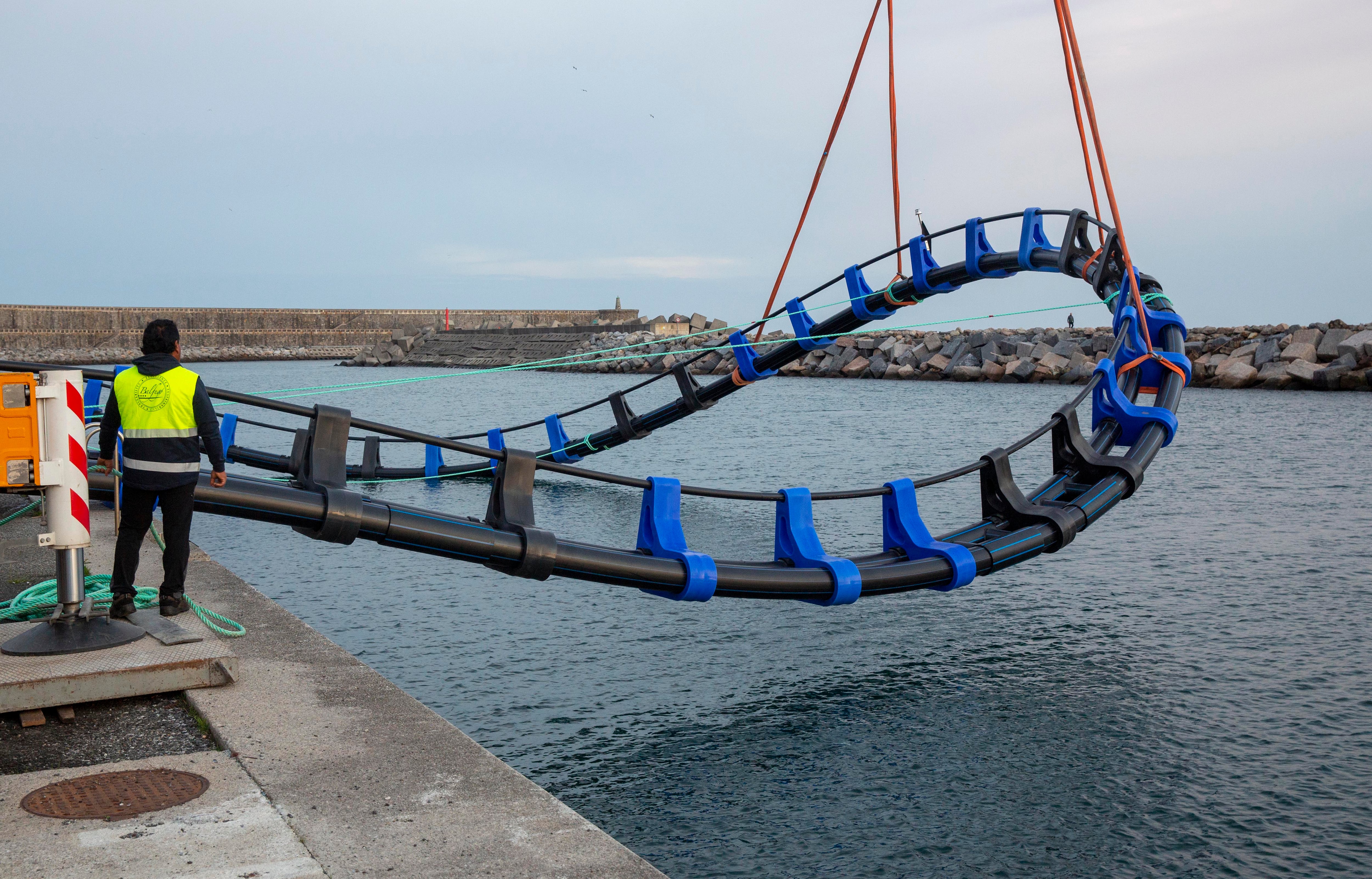 Momento en el que el aro flotante para la cría de atunes se lanza al agua en el puerto de Orio (Gipuzkoa).