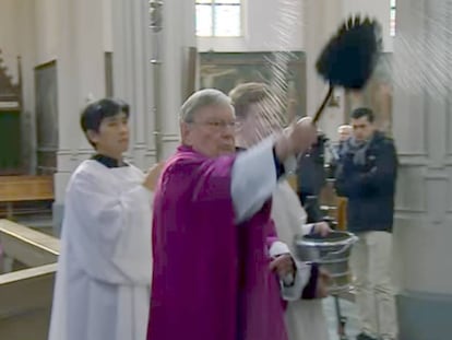 El párroco Jan van Noorwegen rocía con agua bendita el confesionario usado en una de las escenas. La imagen es de un reportaje emitido por la cadena local Omroep Brabant.