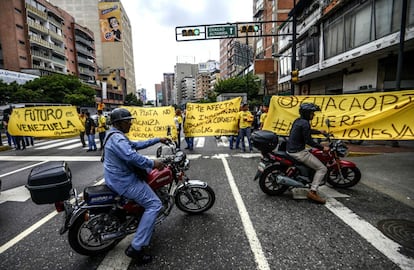 Activistas de la oposición venezolana marchan por una calle de Caracas gritando consignas contra el gobierno del presidente Nicolás Maduro y desplegando pancartas.