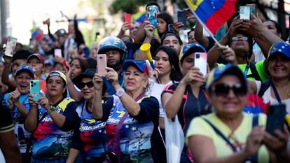 Simpatizantes del candidato opositor Edmundo González observan su paso por las calles de Caracas.