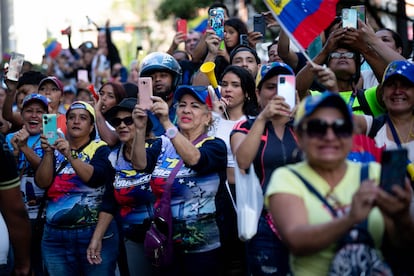 Simpatizantes del candidato opositor Edmundo González observan su paso por las calles de Caracas.
