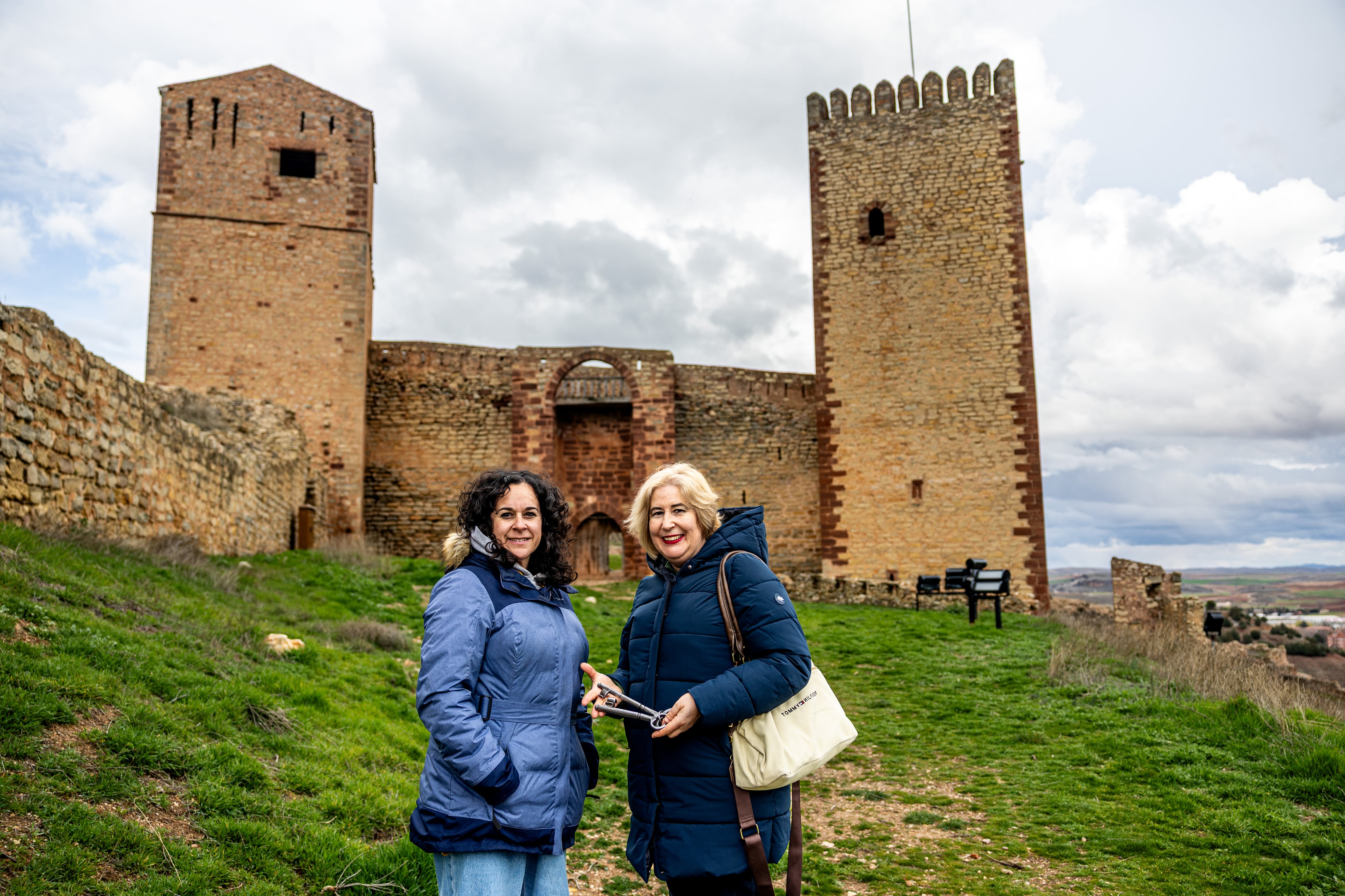 Rocío Andrés (izquierda) y Yolanda Asensio, trabajadoras de la oficina de turismo de Molina de Aragón, posan frente al castillo.