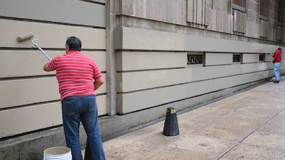 Dos personas pintan un edificio en Ciudad de México.