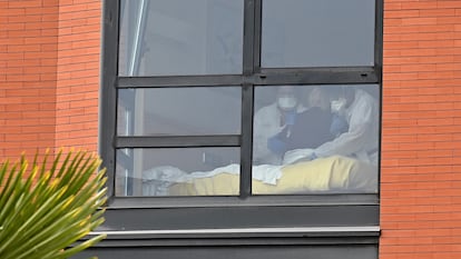 Two workers assist a resident of the Monte Hermoso senior home in Madrid in March.