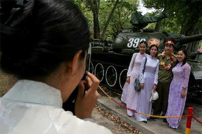 En la imagen, un grupo de estudiantes engalanadas para la fiesta se hacen fotografías junto a un veterano de lo que ellos llaman Guerra Americana ante el Palacio de Reunificación.