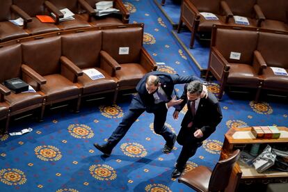 Un miembro de la policía del Capitolio de Estados Unidos sacaba a toda prisa al congresista Dan Meuser de la Cámara de Representantes mientras los manifestantes intentan entrar durante una sesión conjunta del Congreso, el 6 de enero de 2021.