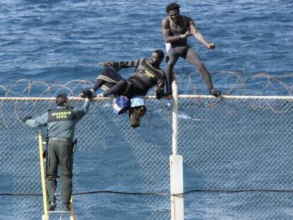 Dos immigrants intenten saltar la tanca de Ceuta davant d'un guàrdia civil en una imatge d'arxiu.