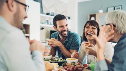 Group of friends gathered around the table with food and drinks, having good time together