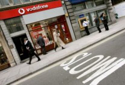 Varias personas pasean junto a una tienda de Vodafone.