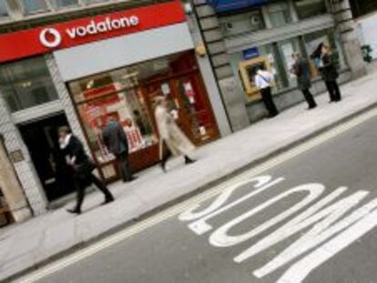 Varias personas pasean junto a una tienda de Vodafone.