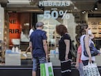 Varias personas observan objetivos del escaparate de una tienda con carteles indicativos de rebajas en Valencia.