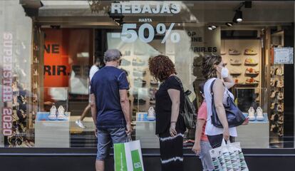 Varias personas ante el escaparate de una tienda en Valencia.