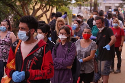 Vecinos hacen cola en el exterior de una escuela utilizada como centro de distribución para personas que necesitan ropa y alimentos en las afueras de Valencia, este lunes.