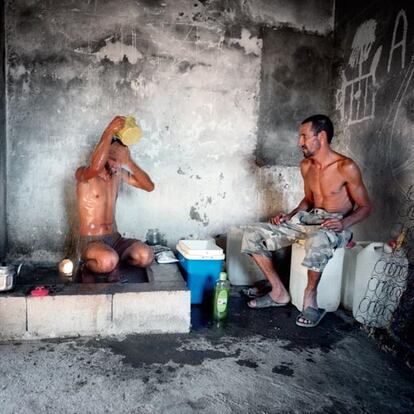 Hassan y Mohamed, de Kenitra (Marruecos), en la 'ducha' que comparten con otros compañeros en un cortijo en ruinas. Deben andar ocho kilómetros parar recoger el agua.