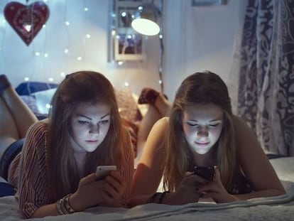 Dos chicas consultan sus móviles.