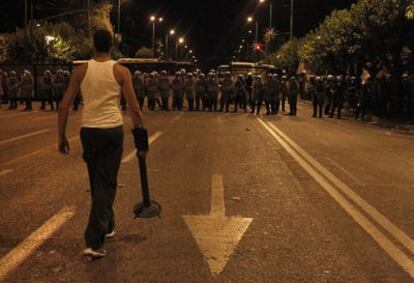 Un manifestante se enfrenta a los grupos policiales antidisturbios que han rodeado las cercanías del Parlamento.