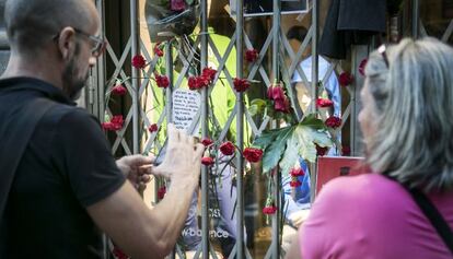 Vecinos en la ofrenda floral del pasado martes a la v&iacute;ctima del Raval. ante una de sus dos tiendas de ropa en el Eixample.