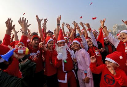 Un grupo de personas, con gorro de Papá Noel, participan en una sesión de yoga de la risa durante la Navidad en una playa de Bombay (India), este sábado.