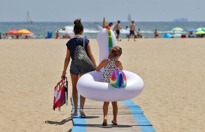 Una niña carga con su flotador hacia la orilla de la playa de Las Arenas de Valéncia. 