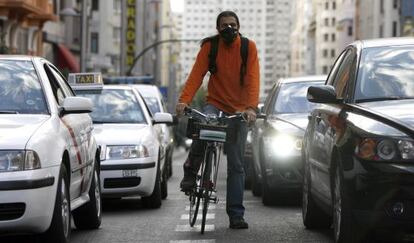 Un ciclista, con m&aacute;scara para protegerse en la Gran V&iacute;a de Madrid