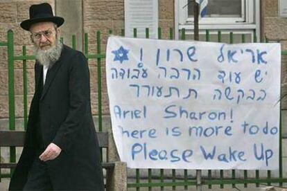 Un judío ortodoxo pasa junto a una pancarta de apoyo a Sharon en el hospital de Hadassah, de Jerusalén.