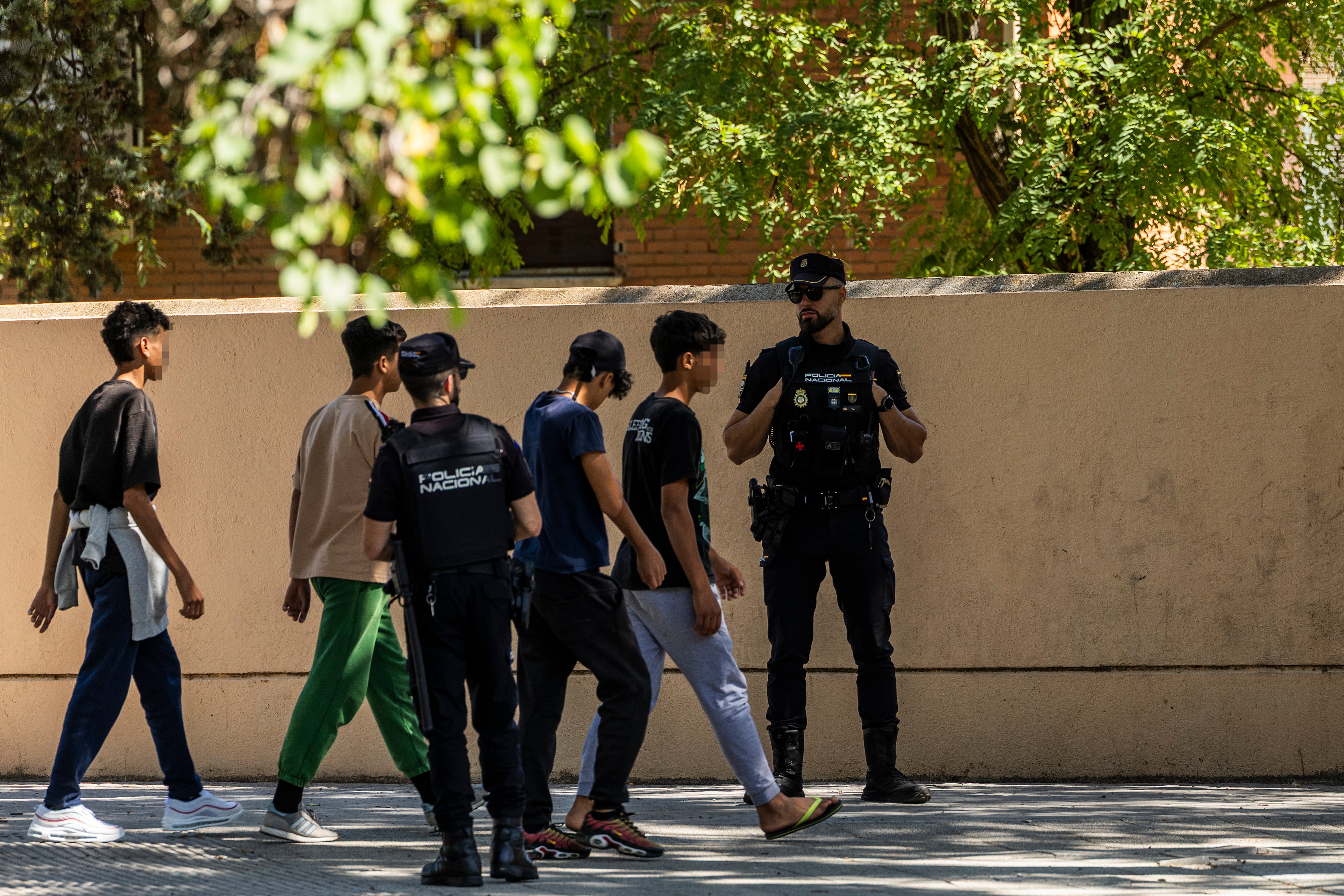 Cuatro menores pasan el jueves delante de dos policías a las puertas del centro de acogida de inmigrantes de Hortaleza, en el noreste de Madrid.