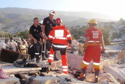 El voluntario Roberto Rubio (de espaldas) habla con un bombero entre los escombros tras el terremoto en Haití.